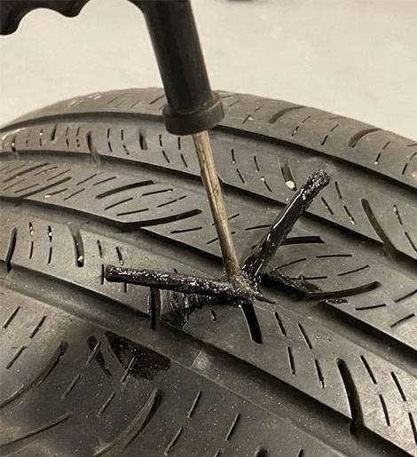 A tire being worked on by a screwdriver.